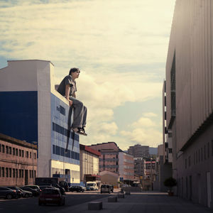Digitally generated image of man sitting on building against sky
