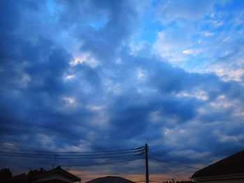 Low angle view of power lines against cloudy sky