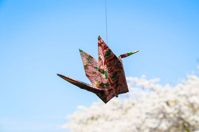 Close-up of paper crane hanging from string against clear blue sky