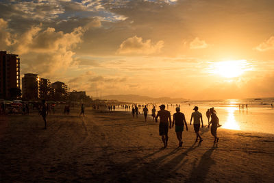 Silhouette people walking on beach during sunset