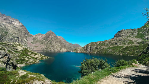 Scenic view of lake and mountains against clear blue sky