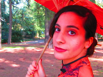 Portrait of beautiful woman holding red while standing outdoors