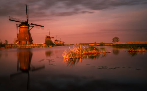 Traditional windmill against sky during sunset