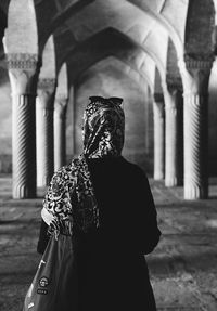 Rear view of man standing outside temple against building