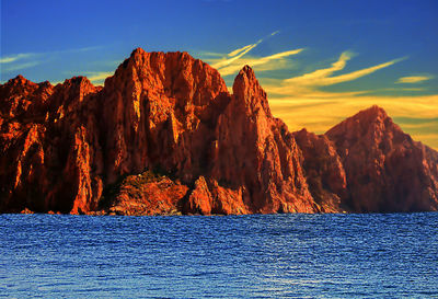 Rock formation by sea against sky during sunset