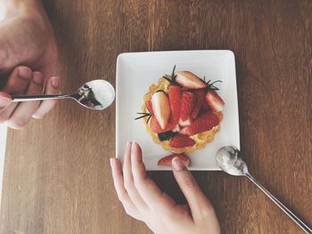 Midsection of person holding ice cream on table