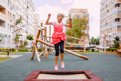 Full length of girl with arms raised in city