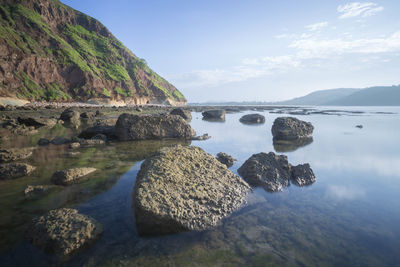 Scenic view of rocks in sea against sky