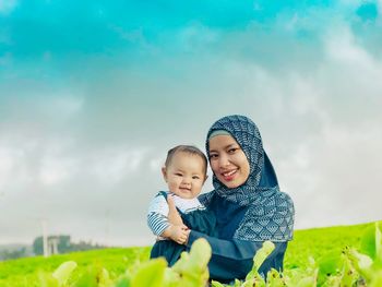 Portrait of mother and daughter on field against sky