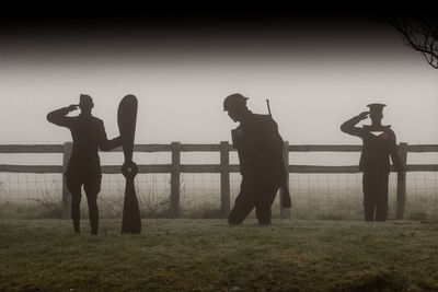 Silhouette people standing on field against sky