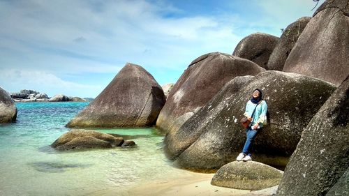 Woman leaning on rock at beach