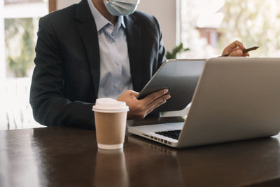 Midsection of man using laptop on table