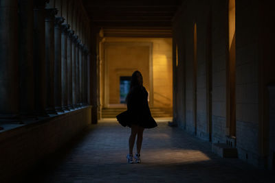 Rear view of woman walking in corridor of building