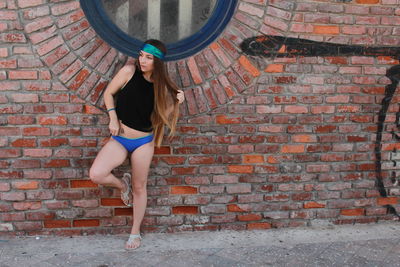 Full length of woman standing against brick wall