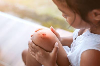 Close-up of girl with wounded knee sitting outdoors