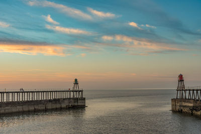 Pier over sea against sky during sunset