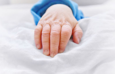 Cropped hand of baby on bed