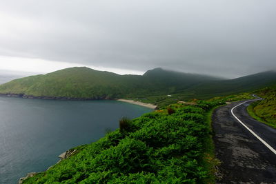 Scenic view of road by mountains against sky