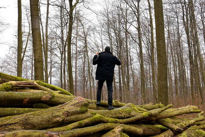 Rear view of mature man standing on logs on forest