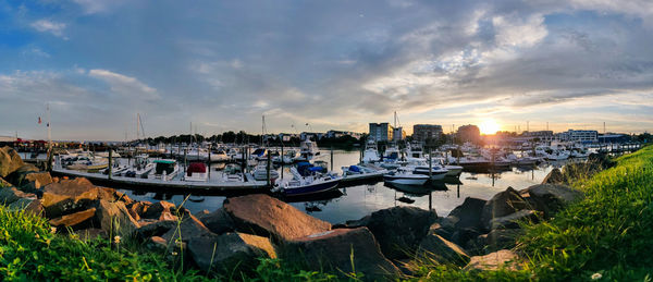Panoramic view of harbor by buildings against sky during sunset