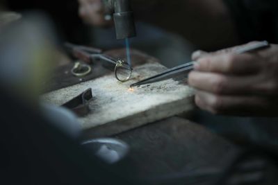 Cropped hand with ring on tweezers on table