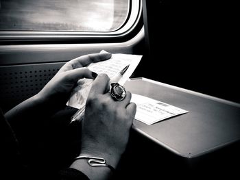 Hands of woman reading postcard in train