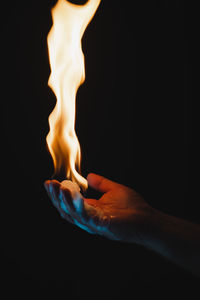 Close-up of burning candle against black background