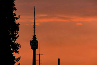 Low angle view of communications tower against orange sky
