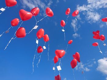 Low angle view of balloons flying against blue sky