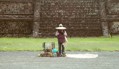 Female vendor standing on road against wall