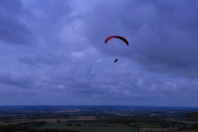 Person paragliding over sea against sky