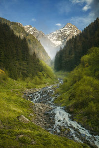 Scenic view of waterfall amidst mountains against sky