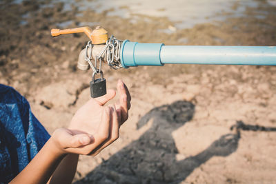 Cropped image of woman with hands cupped under locked faucet