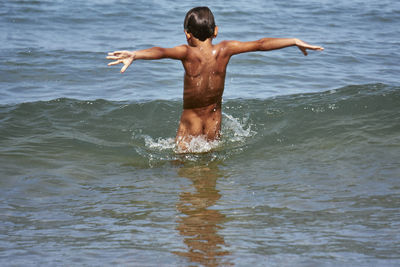 Rear view of shirtless man in sea