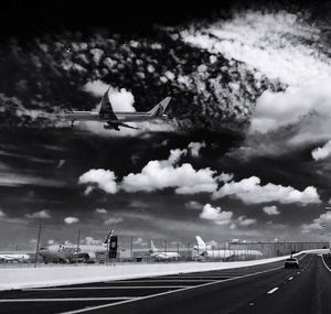 Airplane flying over road against sky