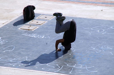 High angle view of mid adult man doing headstand on floor