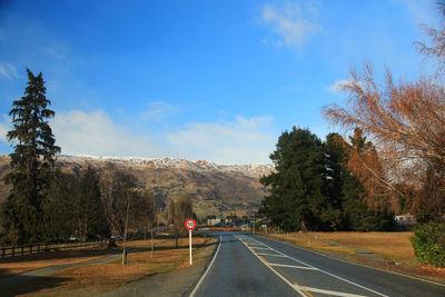Road by trees against sky