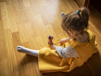 High angle view of girl holding hardwood floor at home