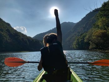 Rear view of woman kayaking in river against sky