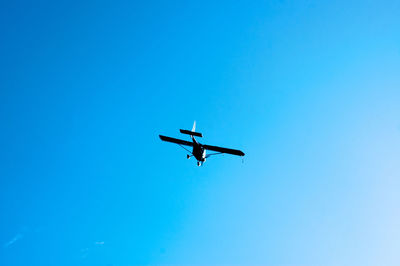 Low angle view of airplane against clear blue sky