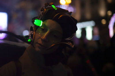 Close-up portrait of man with illuminated lighting equipment at night