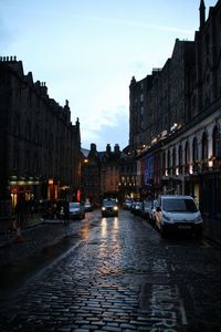 Traffic on road amidst buildings in city at dusk