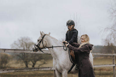 Girl horseback riding with female instructor
