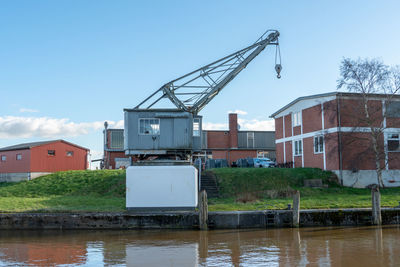 Crane by building against sky