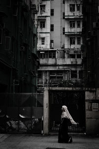 Rear view of woman walking on street amidst buildings