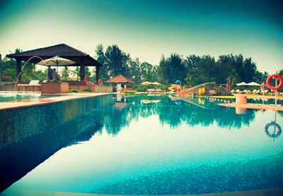 Swimming pool by trees against sky
