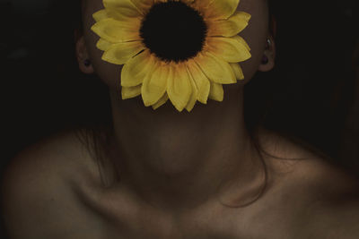 Midsection of topless woman with sunflower