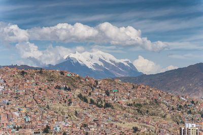 Aerial view of townscape by mountains against sky