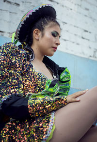 Portrait of young woman standing against wall