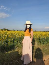 Rear view of woman standing on field against sky